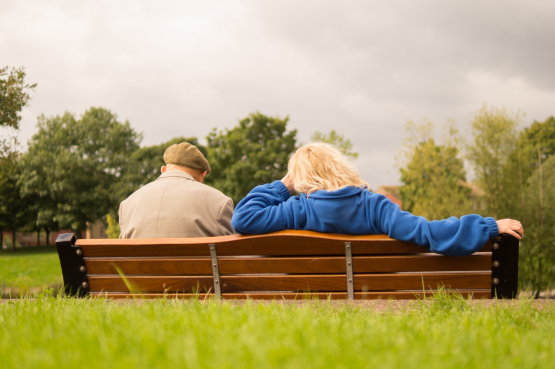 Zwei ältere Menschen sitzen auf einer Parkbank